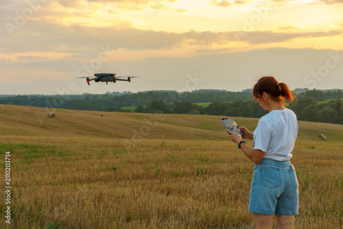 Photography An unmanned aerial vehicle pilot holds a drone control panel in his hands against the background of a hovering drone