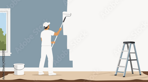 Dedicated male painter in white overalls and cap rolling fresh white paint onto a tall interior wall using an extension roller beside a ladder and paint bucket in a bright renovated room with