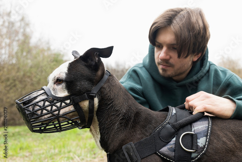 a dog runs in nature with its owner in a muzzle
