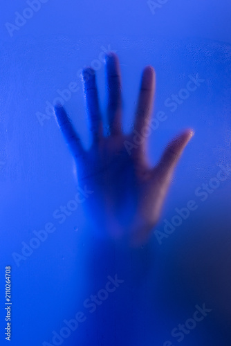 Hand on frosted glass. Anonymous woman reaching out for help concept