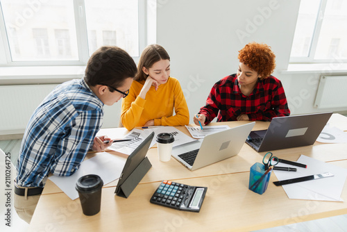 Teamwork brainstorm. Diverse colleagues working together discuss financial statistics. Group of happy young modern people sitting in creative office discussing business. Young professional team