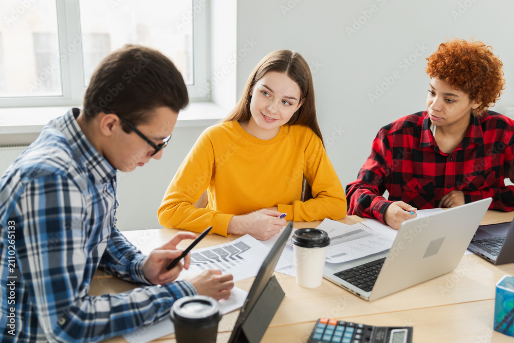 Fototapeta premium Teamwork brainstorm. Diverse colleagues working together discuss financial statistics. Group of happy young modern people sitting in creative office discussing business. Young professional team