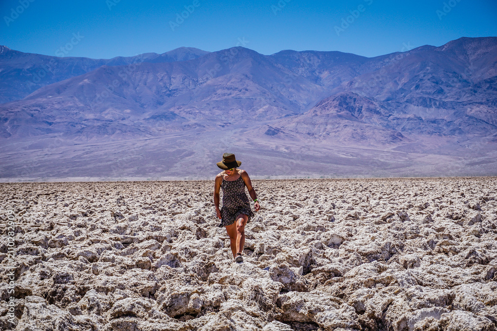 Fototapeta premium Lone traveler walks across cracked, white salt flats