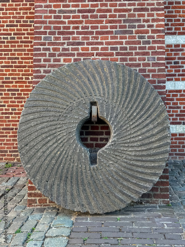Quadro su tela A close-up view of a historic granite millstone displayed against a traditional brick wall