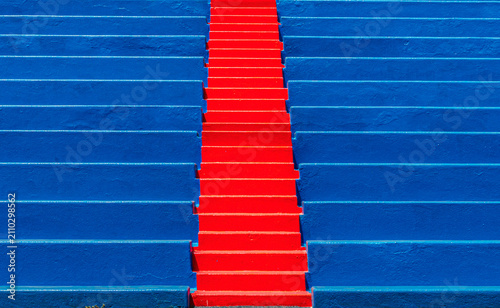 Photography Bright red staircase dividing rows of blue seats in an empty venue