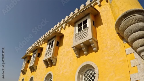 Low angle view revealing the detailed romanticist architecture of the famous pena palace in sintra, portugal, a national monument and a popular tourist destination under a clear blue summer sky