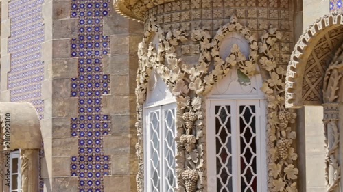 Detailed view of the colorful pena palace facade, highlighting the intricate manueline stonework and the traditional portuguese blue azulejo tiles on a bright sunny day in sintra, portugal