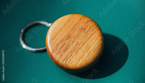 Wooden Round Keychain Resting on Teal Surface.