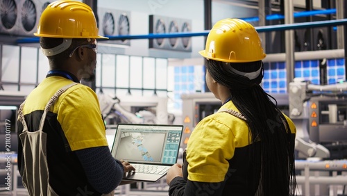 Fotografie A smart solar panel factory engineering team uses laptop to oversee production lines; collaborates smart factory coworkers ensure machinery operates at optimal efficiency using a laptop