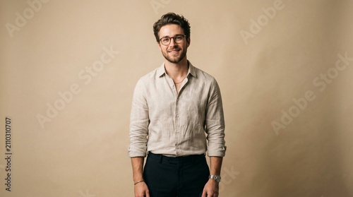 Stylish Young Businessman Wearing Thin Rimmed Eyeglasses and Casual Linen Shirt, Three Quarter Length Portrait on Beige Background, Confident Professional Man Smiling at Camera, Modern Fashion