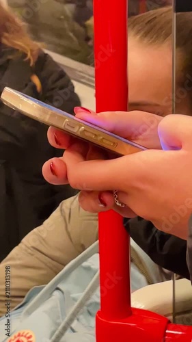 Woman texting crowded, Individual with bright nails engaged in texting during crowded journey, Person with vivid nail polish focused on mobile device. Vertical shot taken on mobile device.