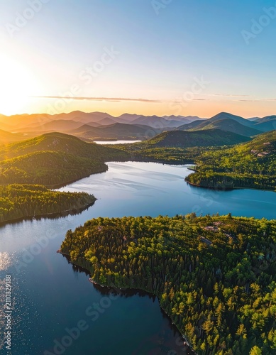 Serene aerial view of a pristine lake and lush green forest at sunset.