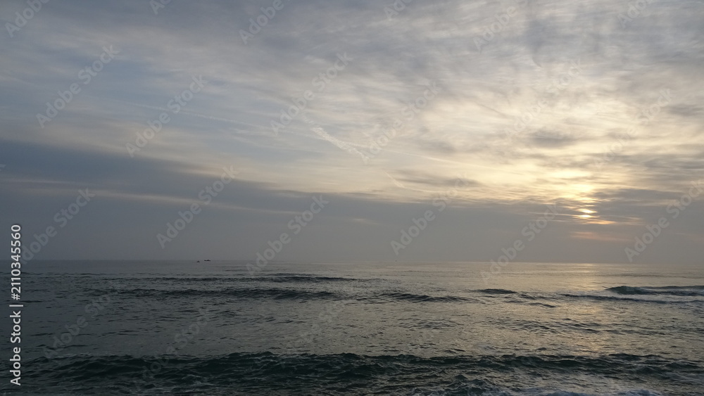Fototapeta premium Wide Morning Sky with Soft Cloud Layers and Quiet Sea Wave. Panoramic view capturing vast textured clouds illuminated by a subtle sunrise glow above gentle waves on the Gangneung coast.