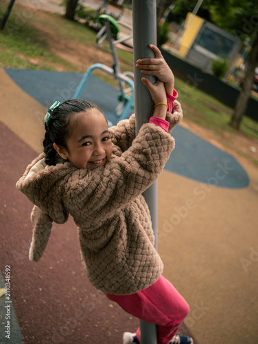 Joyful child climbs a playground pole