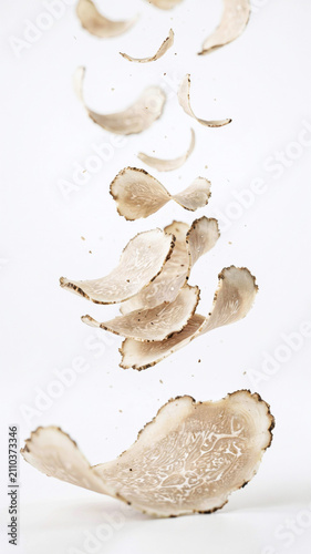 Slices of white truffle (Tuber magnatum) falling from scissors in a clean environment