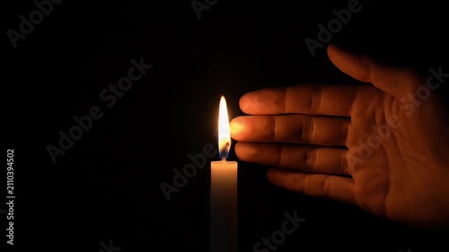 Hand holding a lit candle in a dark room for ambiance.