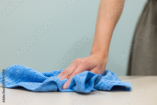 Person cleaning table with blue cloth