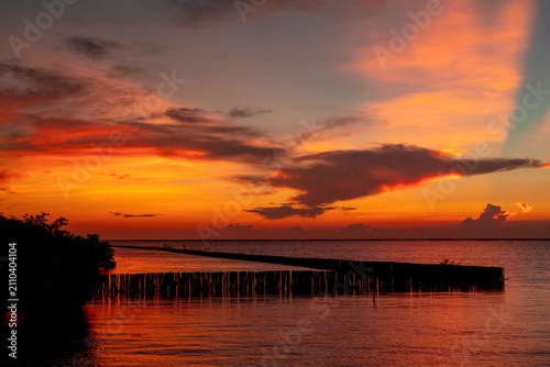 Foto Dramatic sunset sky above the tropical ocean with glowing orange clouds, radiant crepuscular rays, calm water reflections and scenic coastal horizon during a peaceful evening