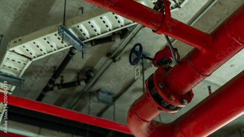 Cuadro en lienzo Red fire protection sprinkler piping network suspended from a modern building ceiling, featuring industrial engineering, fire suppression equipment, safety infrastructure and mechanical installation