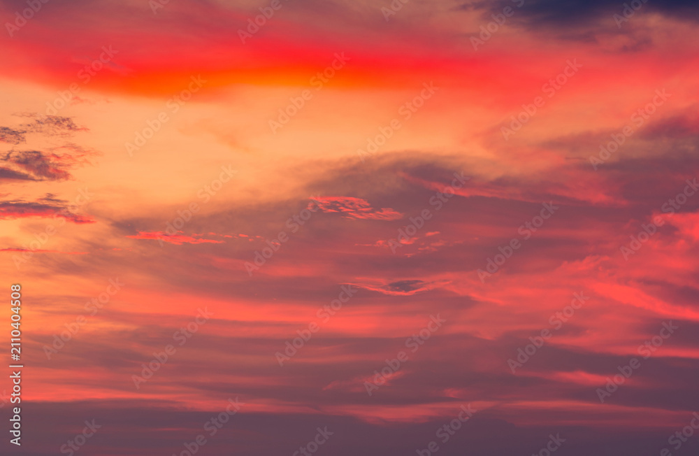 Fototapeta premium Orange and red sunset sky with glowing clouds, dramatic evening atmosphere and colorful cloudscape background. Warm natural weather scene. Nature and background design. Orange and crimson clouds.