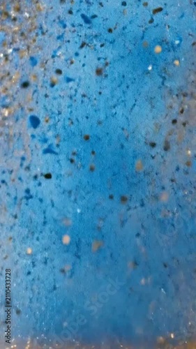 Abstract background featuring shining golden glitter dust particles on blue