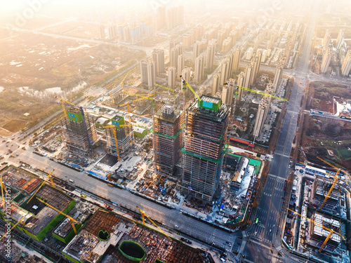 Quadro su tela Aerial shot of an active urban construction site with multiple high-rise buildings under construction, cranes and surrounding city infrastructure