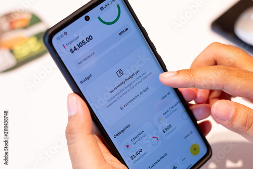 Fotografie Person uses smartphone app for budget and expense tracking on a table