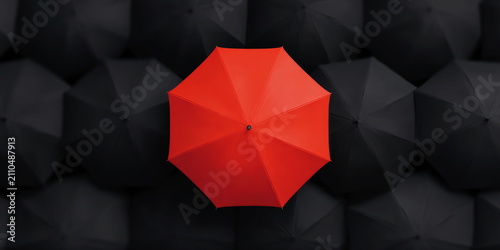 Single bright red umbrella standing out among crowd of black umbrellas representing individuality and power of being different in group