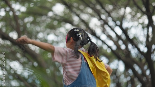 Konstfotografi Happy Asian children playing superhero roleplay with colorful cape and mask outdoors in green park