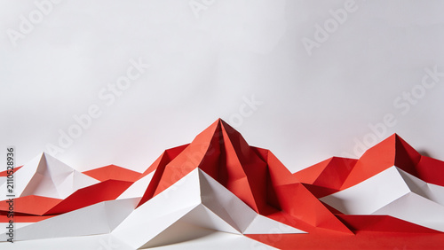 Red and white origami peaks rise against a soft white background