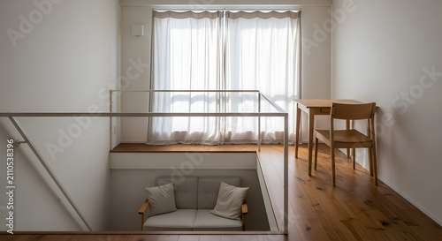 Minimalist interior with modern mezzanine sofa and wooden dining set by large window
