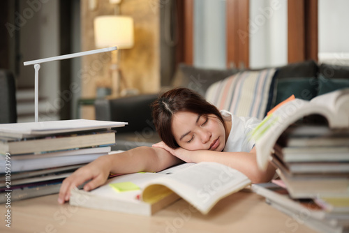 College Asian teenage girl tired and burned out from overwhelmed study pile of books, stressed learning at home with pile of textbooks, reading and writing for school exam, homeschooling education.