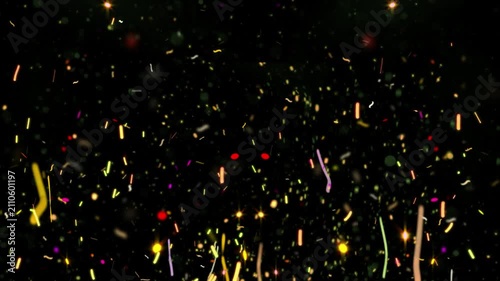 Confetti pieces fall in a dense colorful shower against a deep black background to celebrate a festive occasion or a special event.