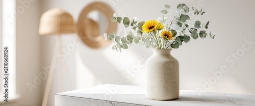 Minimalist vase with eucalyptus and yellow flowers on marble table