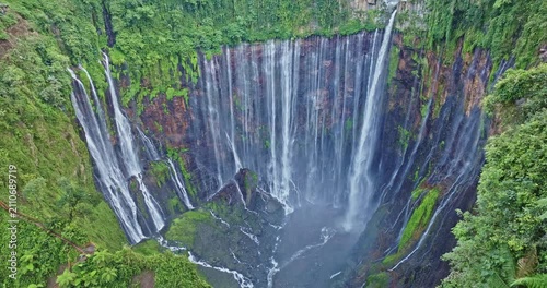 Scenic aerial photography of Indonesia's stunning Tumpak Sewu Waterfall, a world-class travel destination surrounded by lush greenery, volcanic terrain, and dramatic waterfalls.