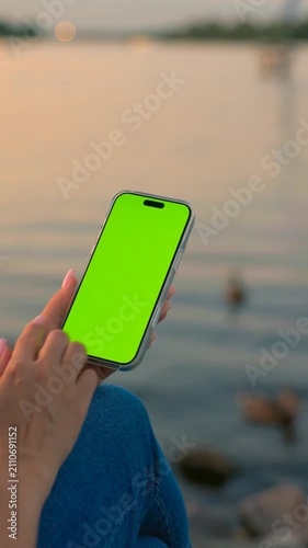 Woman Using Smartphone with Vertical Green Screen Chroma Key Against of River on City Waterfront. Vertical Video