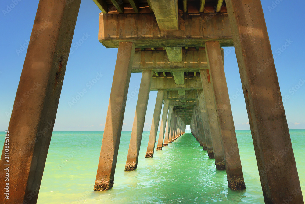 Obraz premium View from under a long concrete pier into the ocean