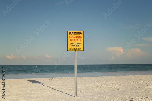 Warning sign for dangerous currents on an empty beach