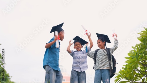 фотографія Happy group of young kids children graduating and celebrating success with graduation caps and diplomas