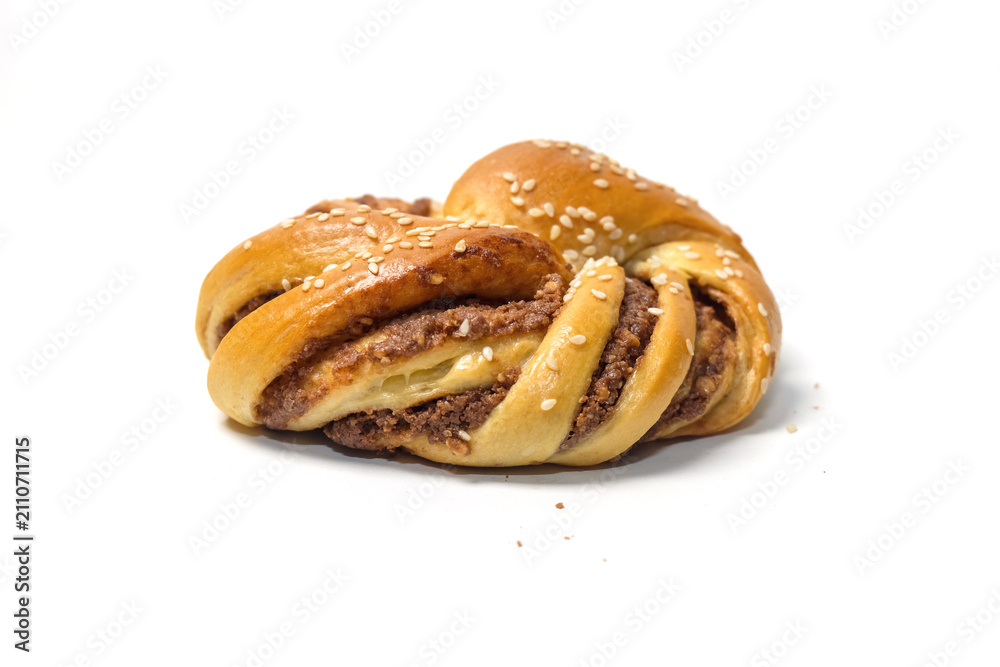 Fototapeta premium Side view of a freshly baked twisted pastry bun filled with chocolate or nut paste and sprinkled with white sesame seeds.