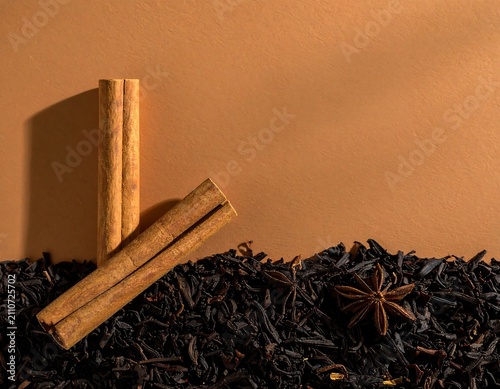 Aromatic Cinnamon Sticks and Star Anise Spices on Loose Black Tea Leaves Against a Brown Background
