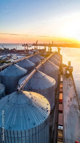 Aerial view captures a storage facility at sunrise, alongside a body of water and a port with cranes