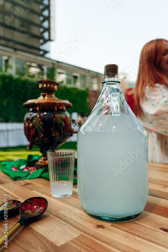 Foto Large glass bottle of traditional russian moonshine samogon on wooden table outd