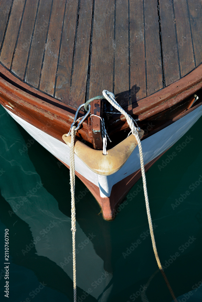 Fototapeta premium A high angle vertical shot of a traditional wooden boat bow with mooring lines and a metal karabiner floating on calm sea water