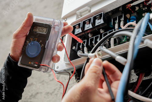Obraz na płótnie 電気工事士がテスターを使い分電盤内の電圧を測定している様子