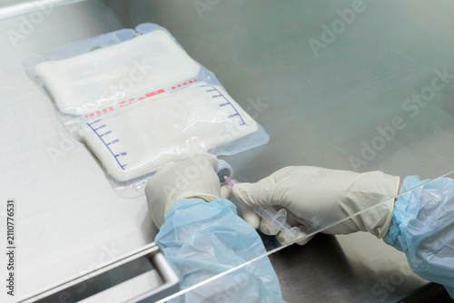 Obraz na płótnie 医療従事者がクリーンベンチ内で輸液パックにシリンジを接続し薬液を注入している様子