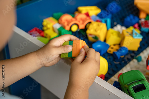 Child assembling colorful building blocks from toy bin