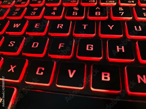 Fotografie Close-up view of qwerty laptop keyboard keys with red led backlighting keyboard