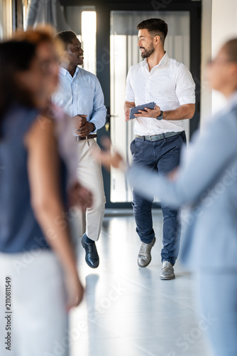 Business colleagues walking and discussing work in modern office hallway