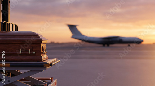 Coffin on a transport cart with airplane in background at sunset  